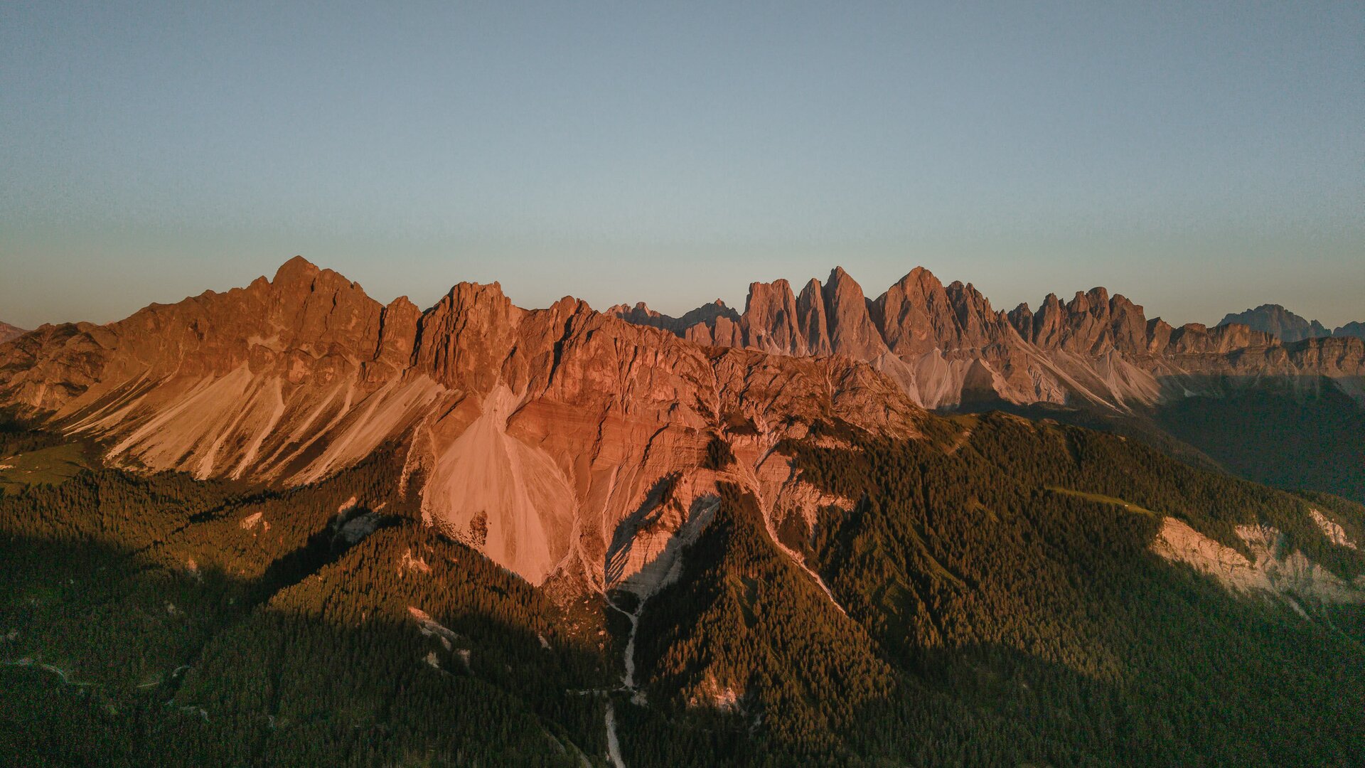 Sonnenaufgang beleuchtet die schroffen Dolomitengipfel über bewaldeten Tälern bei Brixen Südtirol.