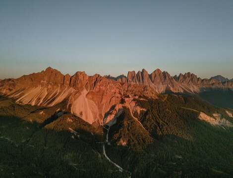 Sunrise lights up the jagged Dolomite peaks above forested valleys near Brixen Südtirol. | © IDM Südtirol-Alto Adige/Luca Putzer
