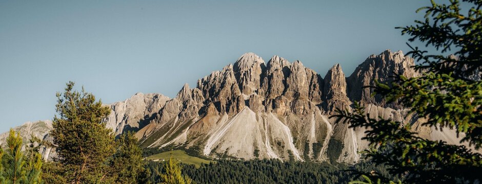 Rocky mountain peaks above forest and meadow in Brixen Südtirol under a clear blue sky. | © (c) IDM Südtirol-Alto Adige/Luca Putzer