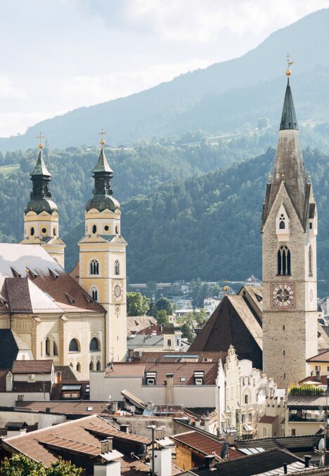 Church towers and rooftops in Brixen Südtirol with green mountains in the background. | © Thomas Rötting