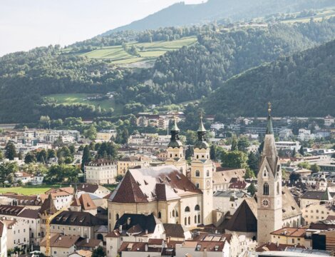 Vista su Brixen Südtirol con il centro storico, i campanili e i pendii verdi.