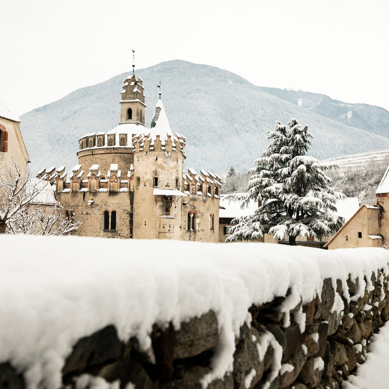 Met sneeuw bedekt kasteel en dorpshuizen in Brixen Südtirol met bergen op de achtergrond. | © Alan Bianchi