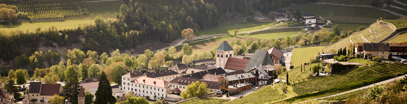 Blick auf ein Dorf in Brixen Südtirol, umgeben von Weinbergen und bewaldeten Hängen im Tal. | © Andreas Tauber