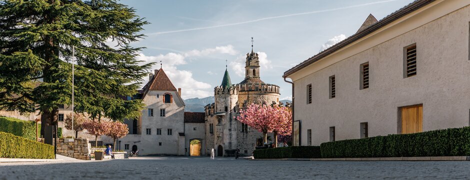 Historischer Platz mit Burgtor, Bäumen und Blüten in Brixen Südtirol