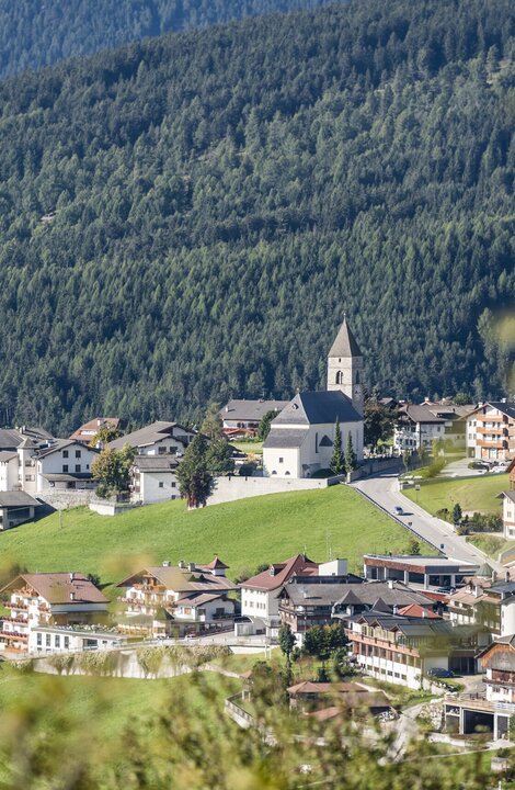 Bergdorf mit Kirche und grünen Wiesen in Brixen Südtirol