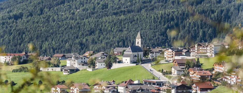 Borgo di montagna con chiesa e prati verdi in Brixen Südtirol
