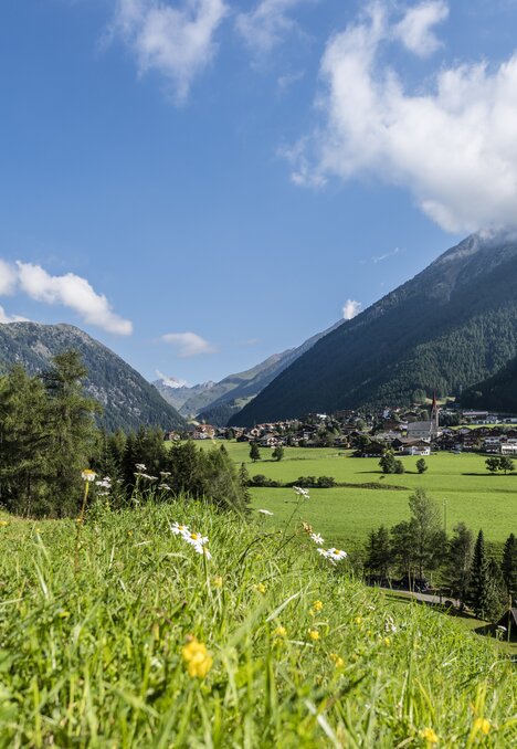 Grünes Tal mit Dorf zwischen Bergen unter blauem Himmel in Brixen Südtirol