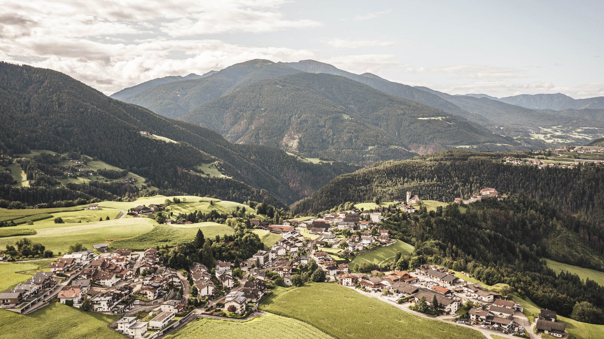 A village in a green alpine valley with mountains rising in the background.