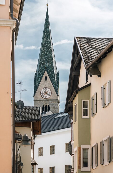 Schmale Altstadtgasse mit Kirchturm zwischen historischen Häusern in Brixen Südtirol.
