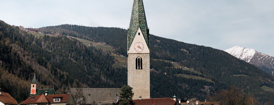 Torre della chiesa sopra un paese con montagne innevate sullo sfondo a Brixen Südtirol. | © Brixen Südtirol Dolomites Italy