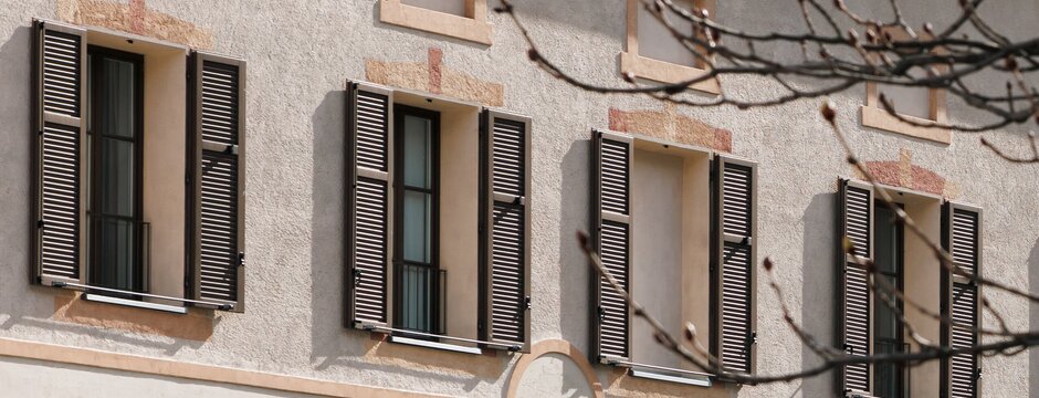 Historische Hausfassade in Brixen Südtirol mit Fensterläden und kahlen Frühlingszweigen