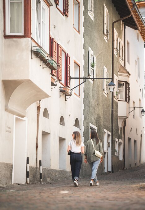 Due donne camminano in una stretta via acciottolata del centro storico di Brixen Südtirol.