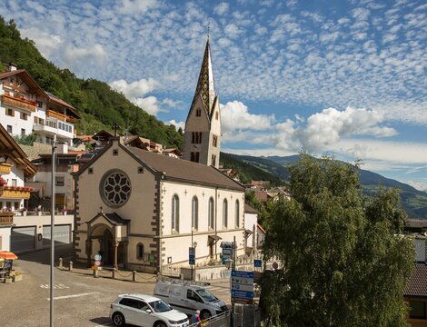 Chiesa in un villaggio di montagna a Brixen Südtirol con case alpine e vista sulla valle