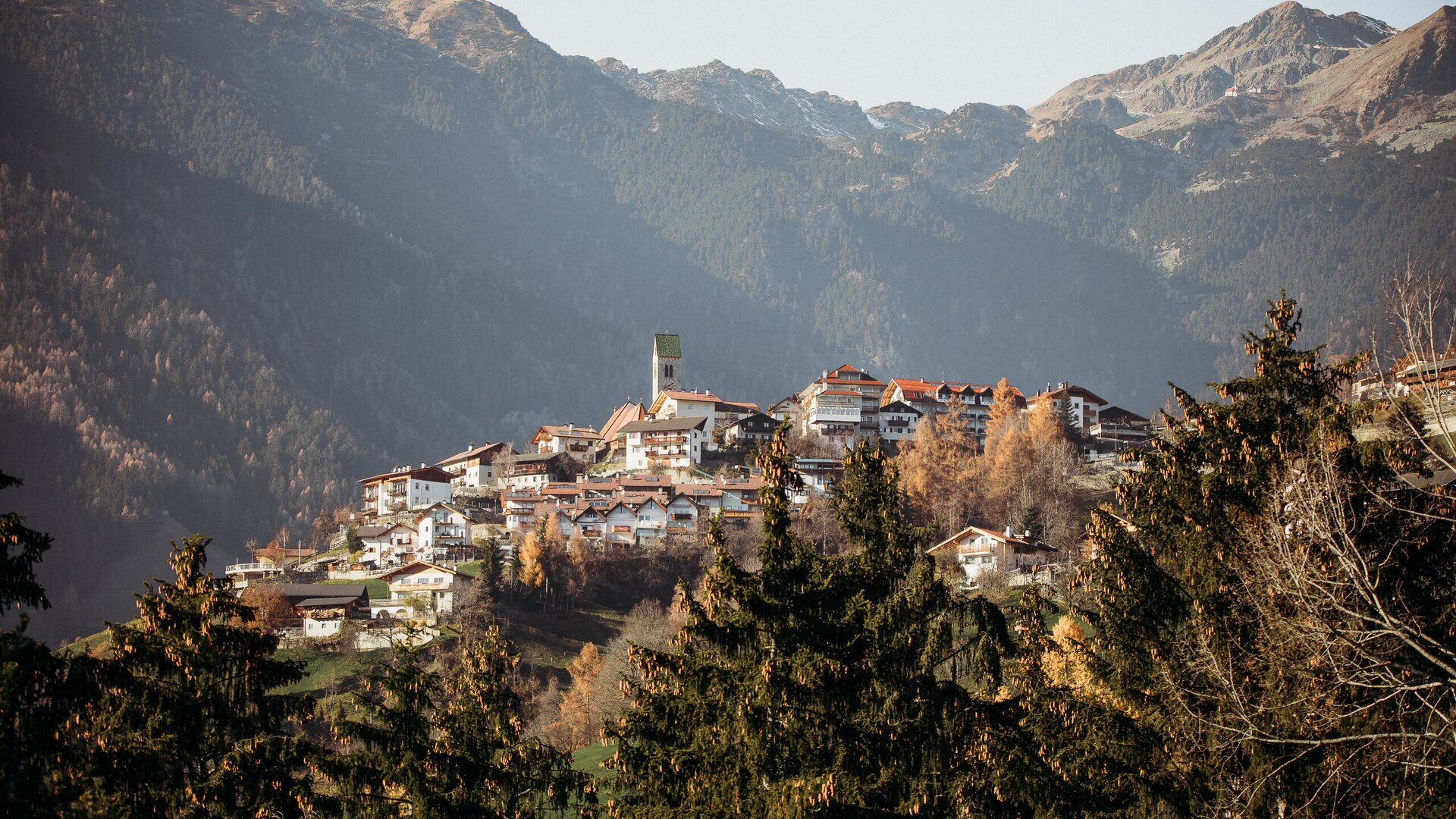 Mountain village in Brixen Südtirol with houses on the hillside below the peaks.