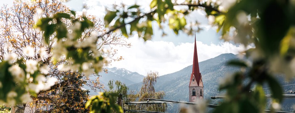 Campanile incorniciato dal fogliame primaverile con le montagne sullo sfondo a Brixen Südtirol.