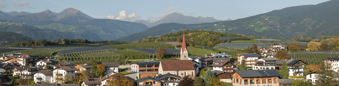 Dorf mit Kirche, Weinbergen und Bergen in Brixen Südtirol