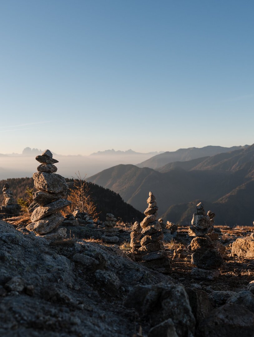 Omini di pietra su una cresta rocciosa al sorgere del sole con cime lontane e cielo limpido