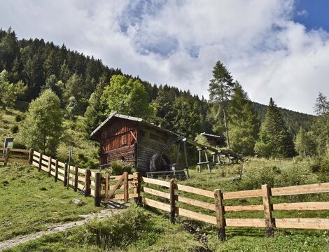Baita in legno accanto a un prato recintato e al bosco a Brixen Südtirol in una giornata estiva.