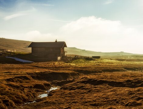 Alpine hut on a sunlit plateau near Brixen Südtirol at sunrise.