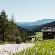 Bergweg an einer Holzhütte mit Blick ins grüne Tal in Brixen Südtirol.