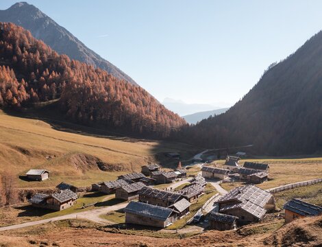 Alpine village in a wide valley near Brixen Südtirol, surrounded by autumn-colored mountains.