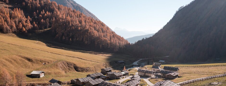 Borgo alpino in una valle ampia vicino a Brixen Südtirol, circondato da montagne dai colori autunnali.