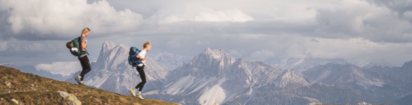 Two hikers on a mountain ridge with panoramic alpine views in Brixen Südtirol