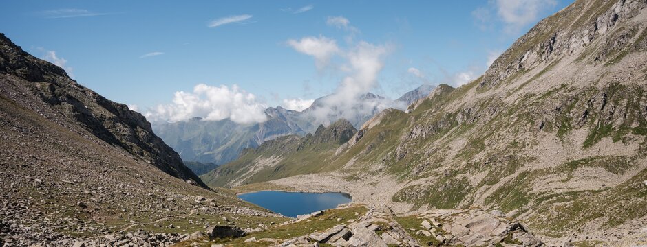 Alpensee in einem felsigen Bergtal unter klarem blauen Himmel.