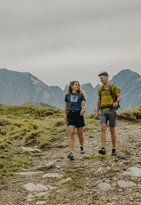 Due escursionisti camminano su un sentiero di montagna su un altopiano erboso vicino a Brixen Südtirol.