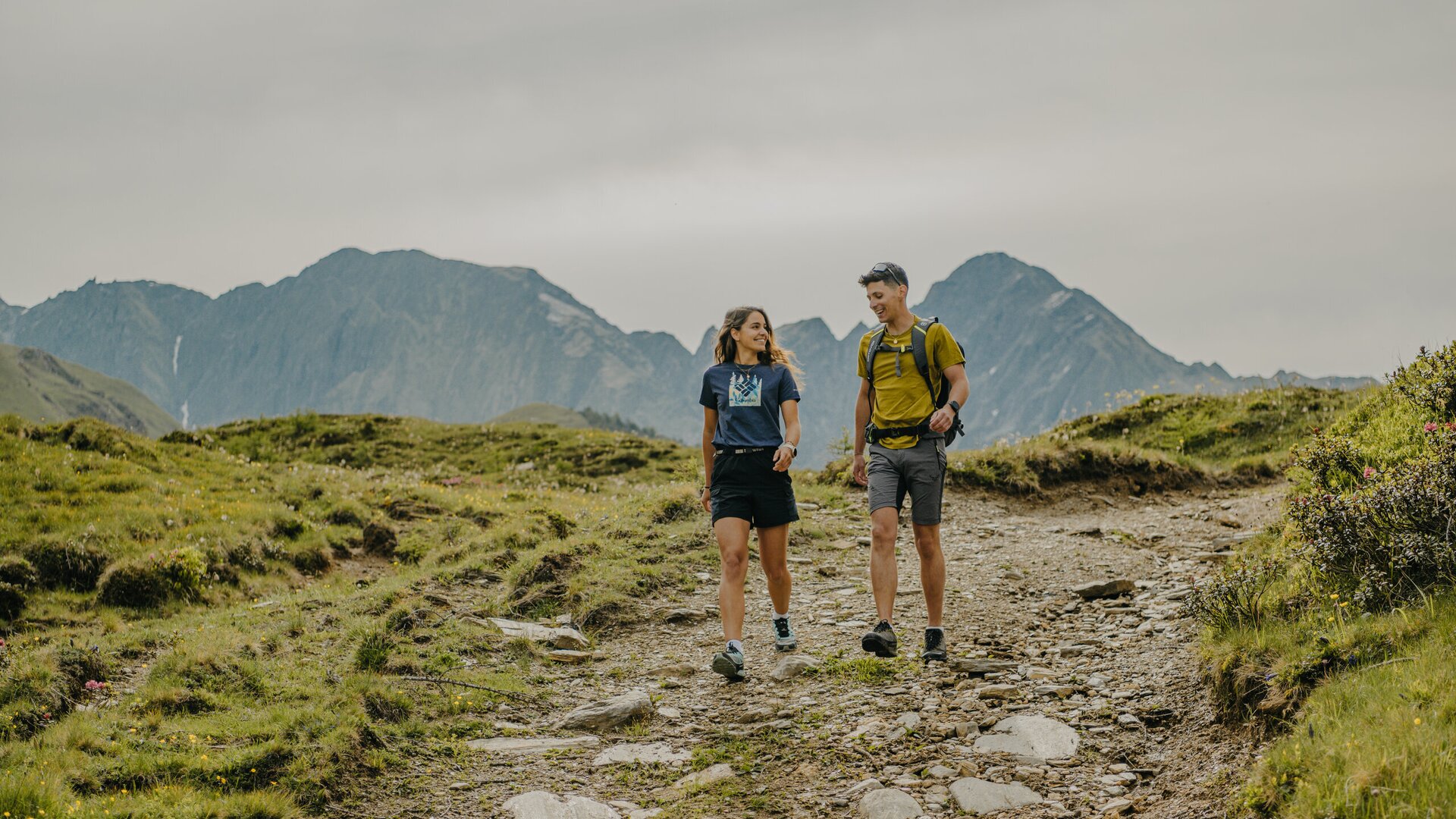 Two hikers walking along a mountain trail on a grassy plateau near Brixen Südtirol.