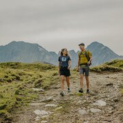 Two hikers walking along a mountain trail on a grassy plateau near Brixen Südtirol.