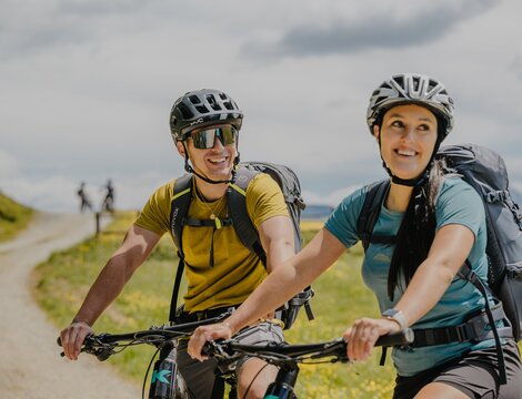 Due ciclisti con casco e zaino percorrono un sentiero di montagna a Brixen Südtirol.
