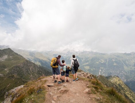 Familie mit Kindern beim Wandern auf einem Berggrat mit Blick ins Tal.