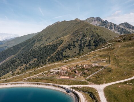 Bergpfad über einem türkisfarbenen See auf einer grünen Almhochfläche