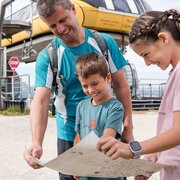 Famiglia che guarda una mappa alla stazione della funivia a Brixen Südtirol prima di un'escursione.
