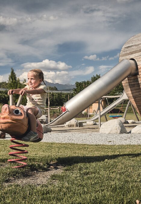 Child riding a spring rocker at a wooden playground in Brixen Südtirol