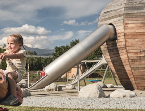 Bambino su un gioco a molla in un parco giochi in legno a Brixen Südtirol