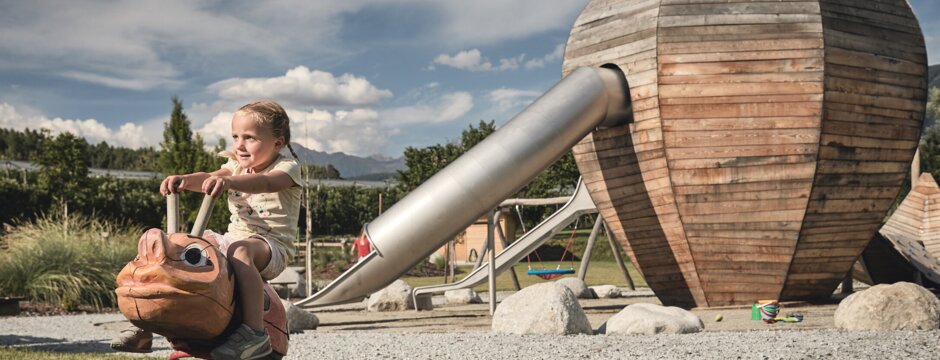 Kind auf einem Federwippgerät an einem Holzspielplatz in Brixen Südtirol