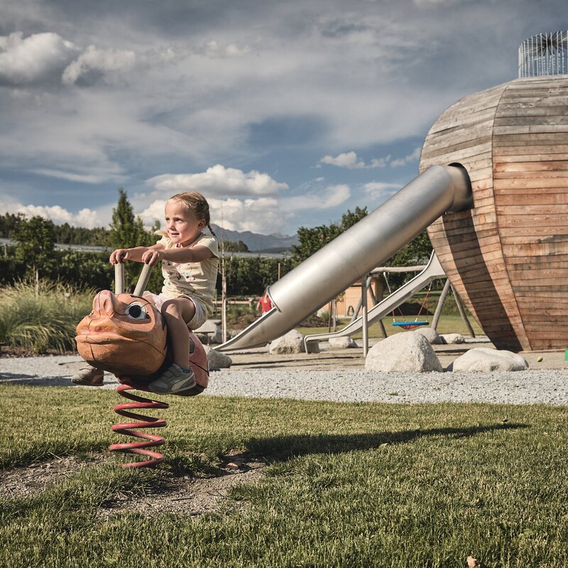 Kind auf einem Federwippgerät an einem Holzspielplatz in Brixen Südtirol