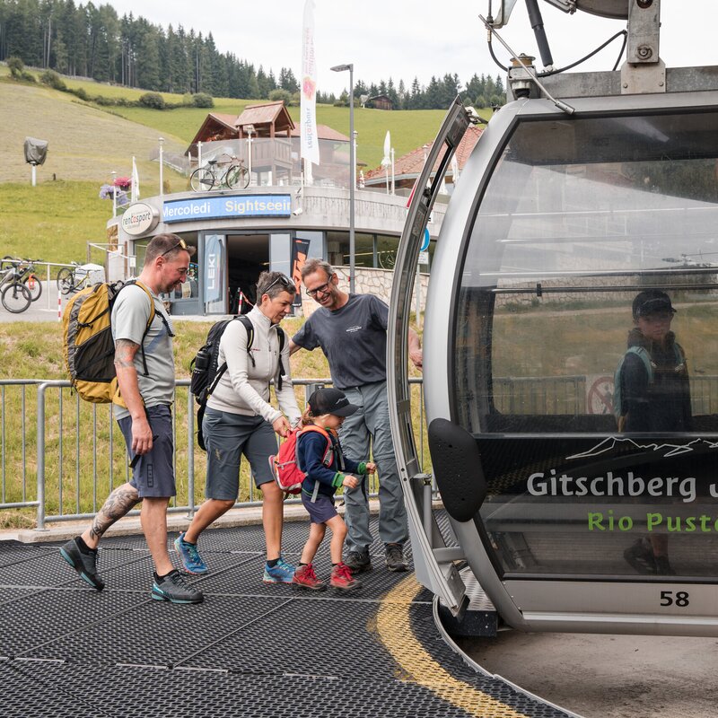 Famiglia che sale sulla funivia a Gitschberg Jochtal tra i monti estivi.