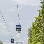 Cabinovie sopra una valle verde con le montagne sullo sfondo.