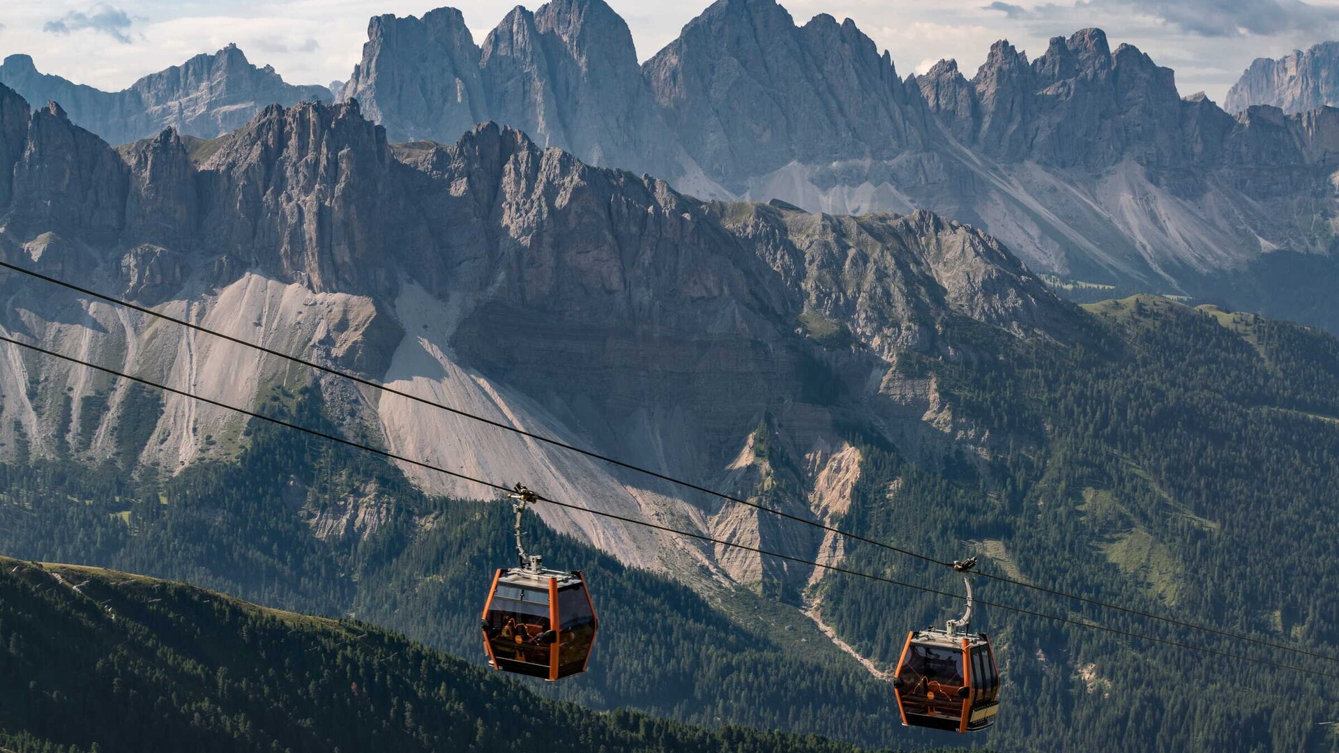 Cable cars glide above the valley with dramatic Dolomite peaks in Brixen Südtirol.