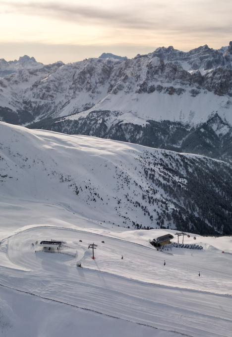 Pendii innevati sotto le cime alpine frastagliate nella luce dell’alba.