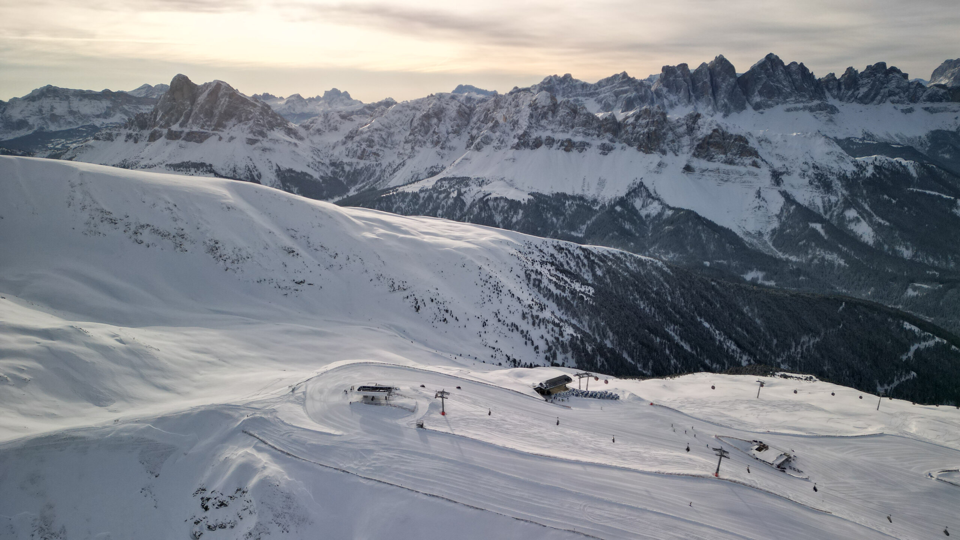 Pendii innevati sotto le cime alpine frastagliate nella luce dell’alba.