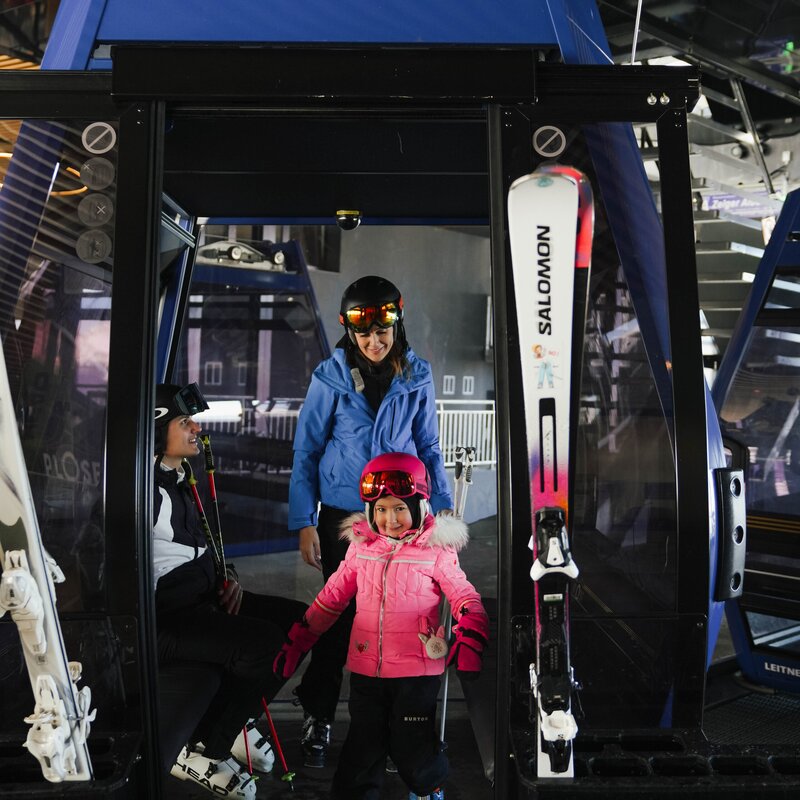 Famiglia con bambino in una cabinovia da sci, pronta per la salita in inverno.