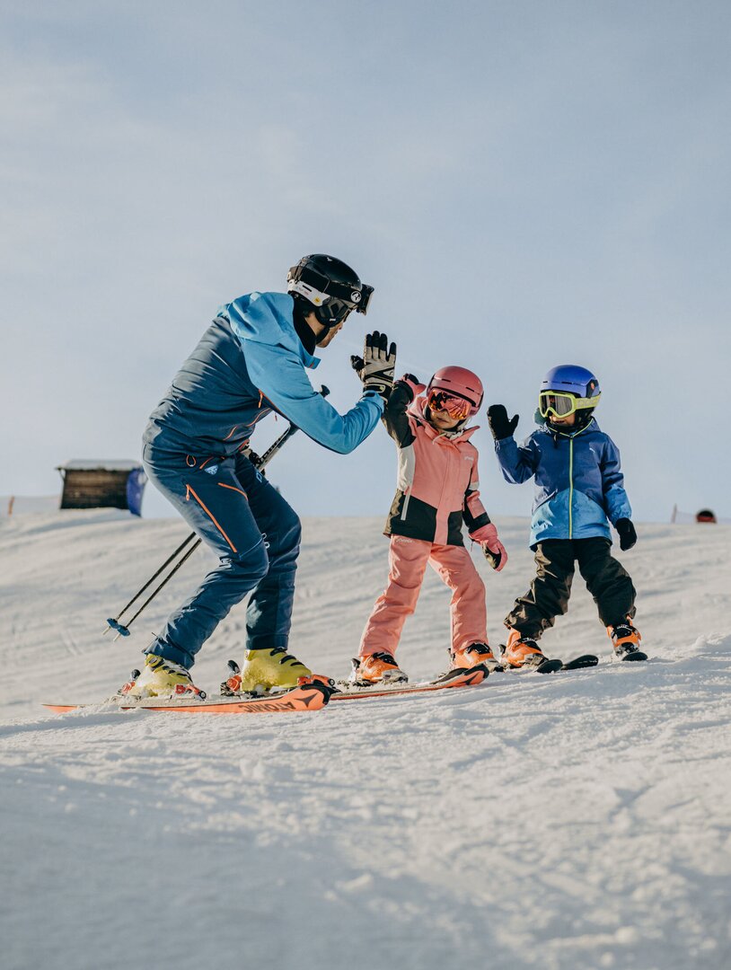 Maestro di sci aiuta due bambini su una pista innevata
