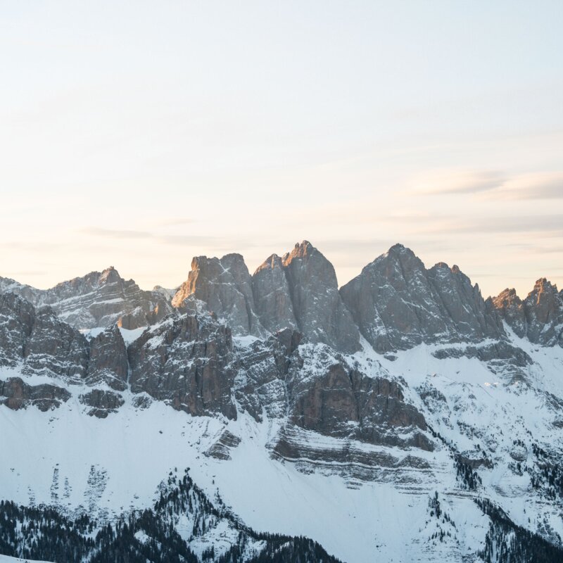 Besneeuwde bergtoppen boven een dal bij zonsopgang in de regio Brixen Südtirol.