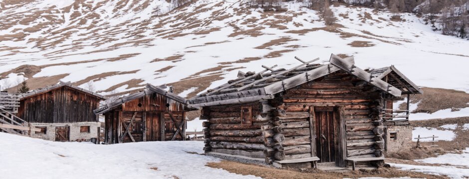 Met sneeuw bedekte berghutten in een bergdal met rotsachtige hellingen op de achtergrond.
