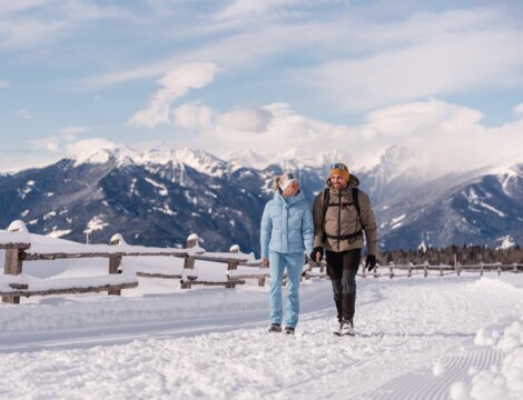 Twee wandelaars lopen over een besneeuwd pad met uitzicht op de bergen in Brixen Südtirol.