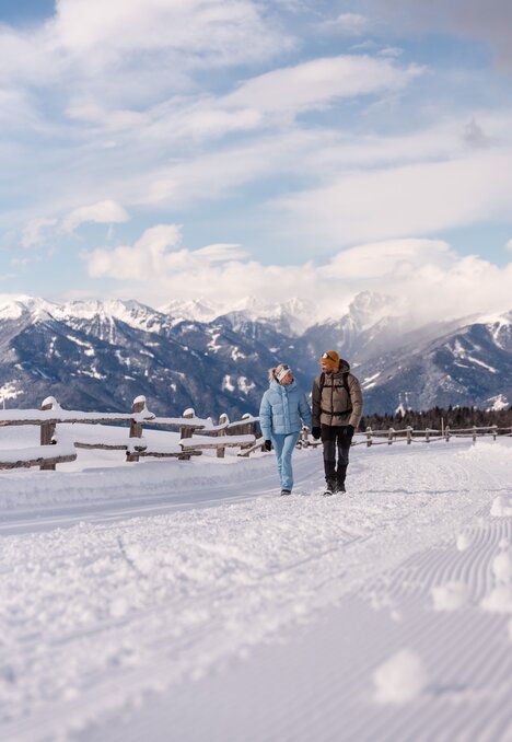Zwei Personen gehen auf einem verschneiten Weg mit Bergblick in Brixen Südtirol.